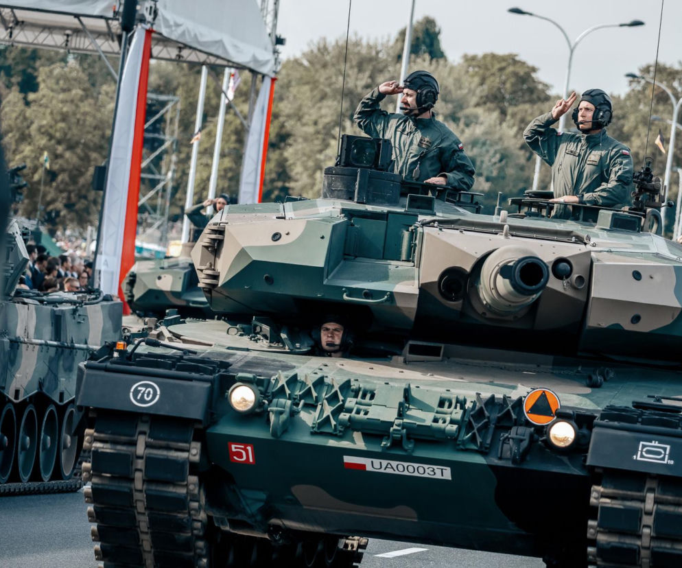 Dwaj czołgiści salutujący z wieży Leopard 2PL podczas defilady. O polskiej pancernej pięści przeczytasz na SE Portal Obronny.