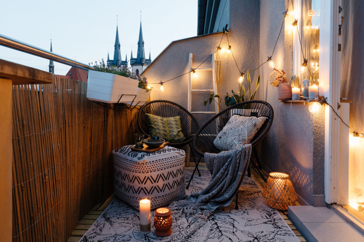 Mały balkon w bloku lub kamienicy z czarnym rattanem.