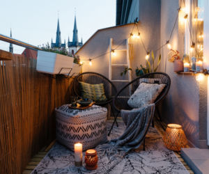 Mały balkon w bloku lub kamienicy z czarnym rattanem.
