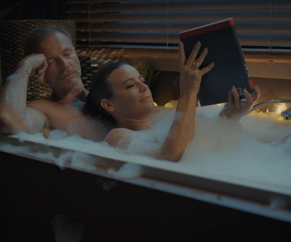 Magda (Anna Mucha) z Andrzejem (Krystian Wieczorek) z serialu M jak miłość relaksują się w wannie pełnej piany. Magda leży i czyta książkę, podczas gdy Andrzej, zmęczony, opiera głowę na ręce i przysypia. Ten intymny moment to ukojenie po trudnym dniu, o którym przeczytasz więcej na Super Seriale.