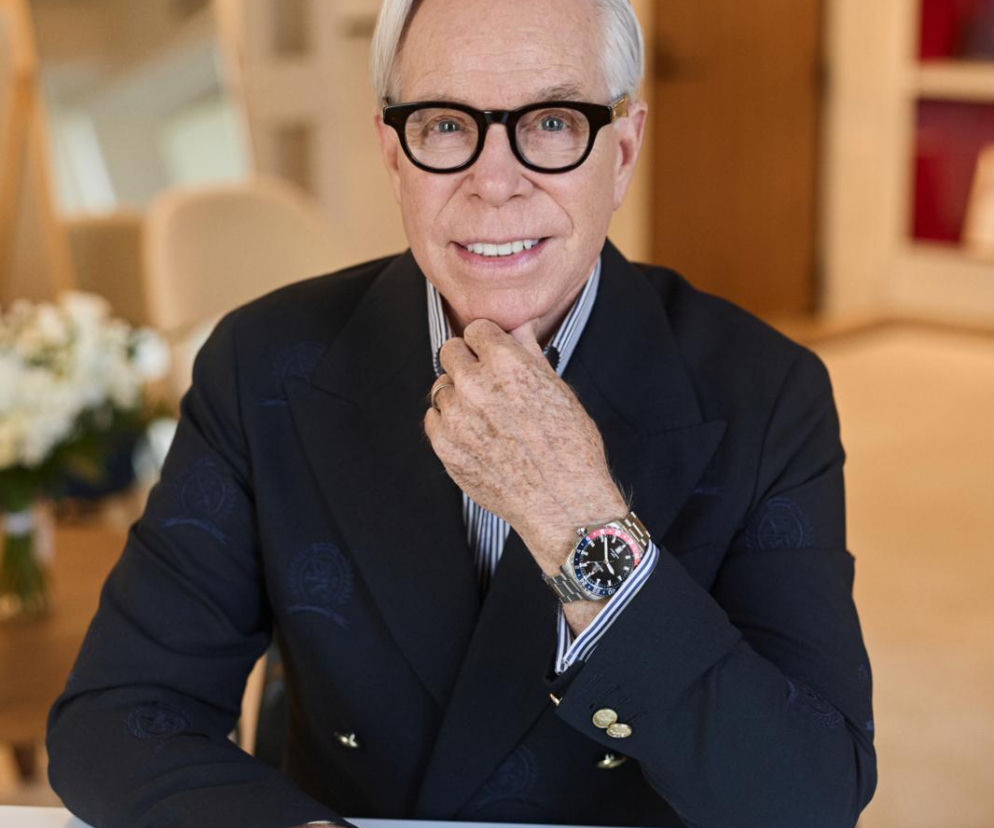 Projektant Tommy Hilfiger w okularach MR. HILFIGER 01 siedzi przy stole. O nowej kolekcji przeczytasz na SE.