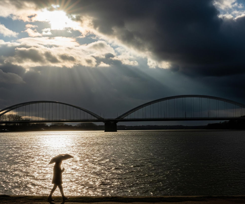 Na pierwszym planie, w dolnej części obrazu, widoczna jest sylwetka osoby idącej w lewo, trzymającej otwarty parasol. Osoba ta jest częściowo podświetlona przez słońce, co sprawia, że jej kształt jest rozmyty i otoczony złotą poświatą. W tle rozciąga się szeroka rzeka, której powierzchnia mieni się złotym blaskiem odbijającego się słońca. Dalej, nad rzeką, znajduje się most łukowy z dwoma dużymi przęsłami. Horyzont dominuje pochmurne niebo, z ciemnymi, burzowymi chmurami po prawej stronie i jaśniejszymi, podświetlonymi słońcem po lewej, skąd promienie światła przenikają przez rozstępy w chmurach.