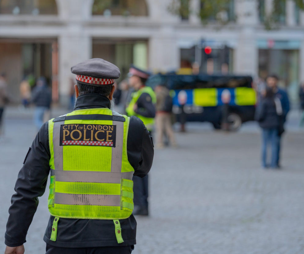 Policjant tyłem w kamizelce City of London Police. O ochronie premiera w Manchesterze przeczytasz na SE Portal Obronny.