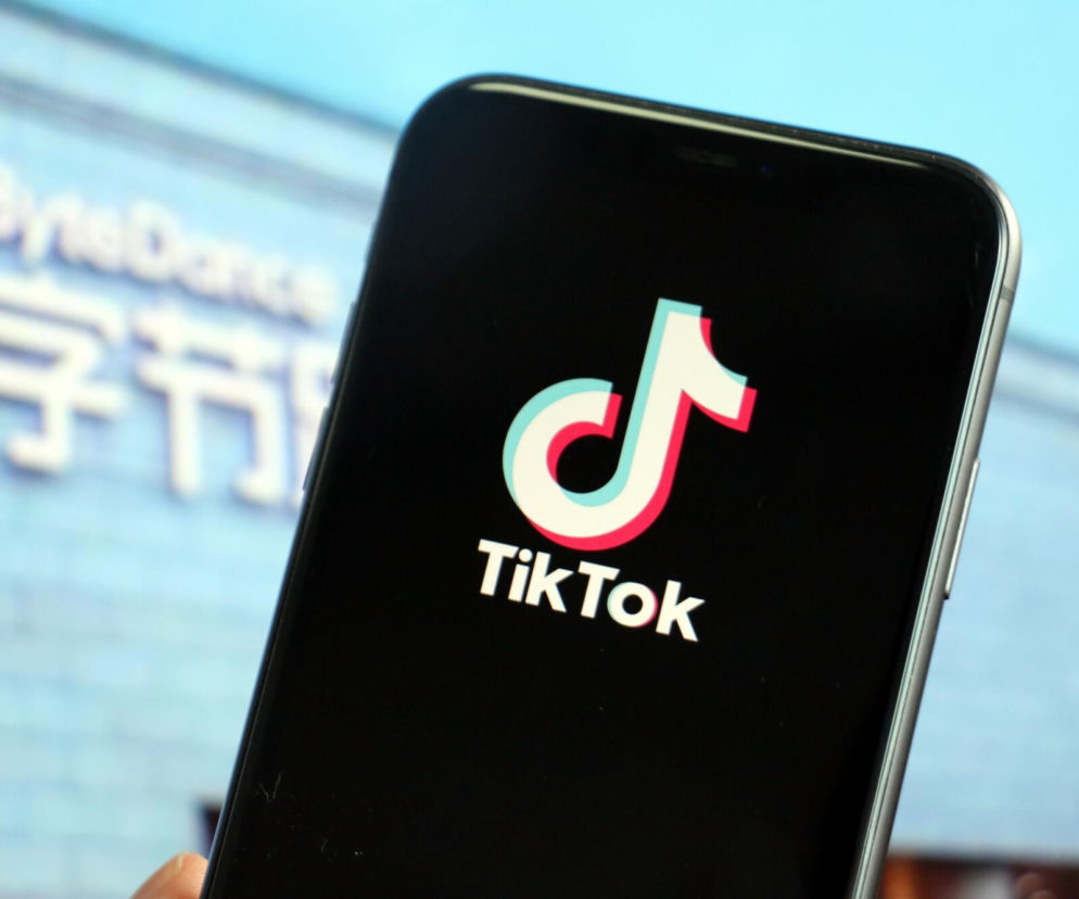 Smartfon z logo aplikacji TikTok. W tle rozmyty napis ByteDance. O raporcie NASK dotyczącym TikToka przeczytasz na Eska.