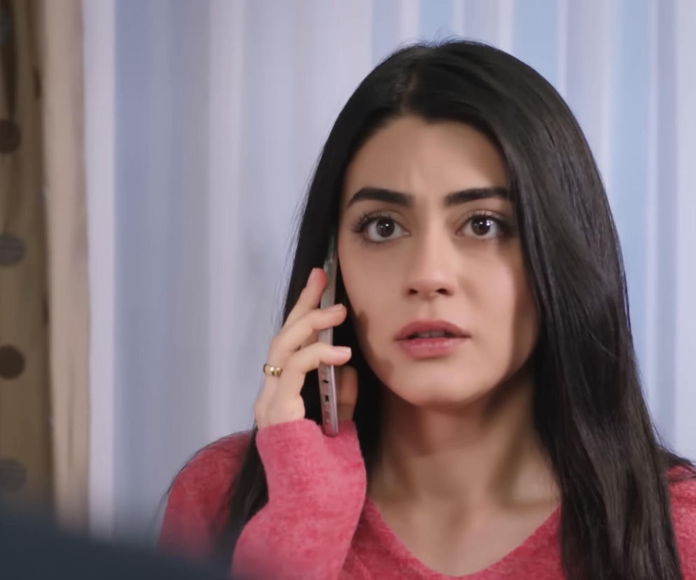 Hancer w różowym swetrze, z długimi ciemnymi włosami i zdziwioną miną, trzymająca telefon przy uchu. Scena z tureckiego serialu Panna młoda, gdzie Hancer odbiera telefon od byłej żony Cihana. Więcej o serialu Panna młoda znajdziesz na Super Seriale.