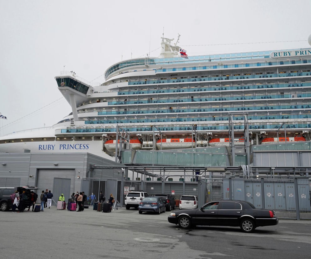 Wycieczkowiec Ruby Princess w porcie. Pasażerowie z bagażami przed statkiem. O epidemii na pokładzie przeczytasz na SE.