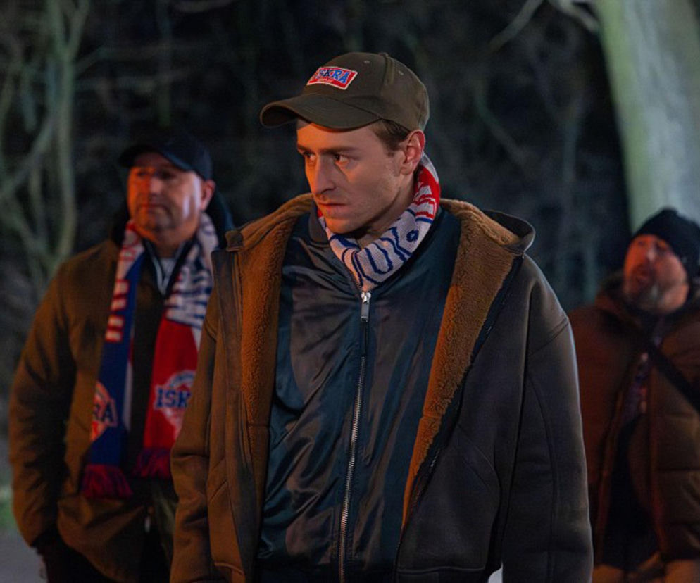 Mężczyzna w czapce z daszkiem i zimowej kurtce, otoczony dwoma innymi mężczyznami, najprawdopodobniej członkami grupy kiboli, których Darek z serialu Pierwsza miłość manipuluje w odcinku 4211. Więcej na ten temat znajdziesz na Super Seriale.