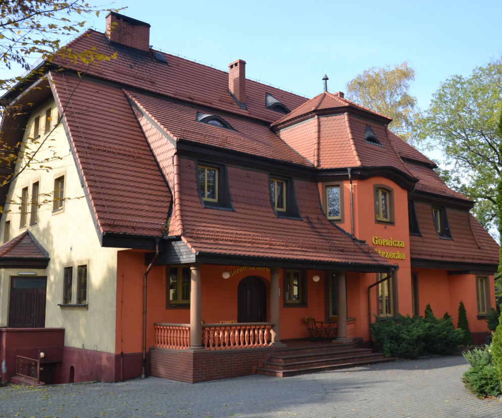 Zabytkowy budynek z pomarańczową elewacją i wielospadowym dachem w Radlinie. O architekturze miasta przeczytasz na Eska Śląskie.