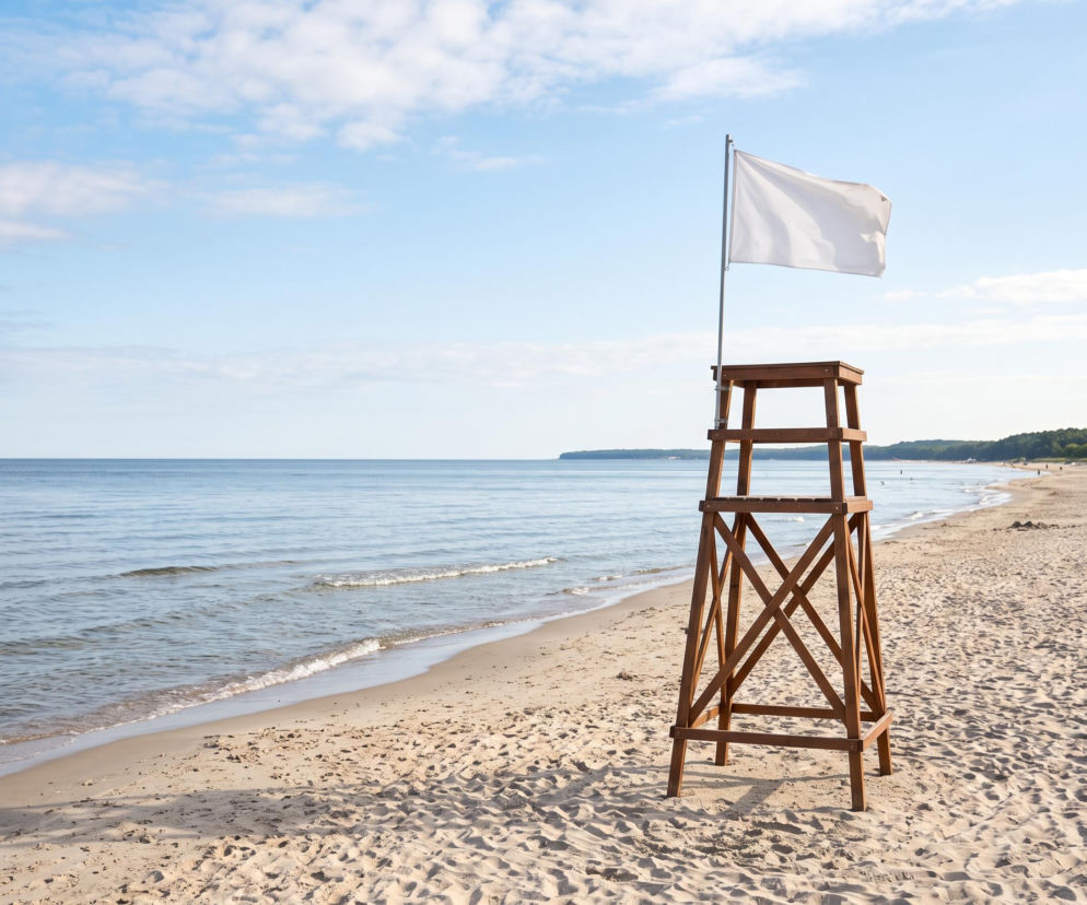 Drewniana wieża ratownika z białą flagą na plaży w Międzyzdrojach. O bezpieczeństwie w wodzie przeczytasz na SE Szczecin.