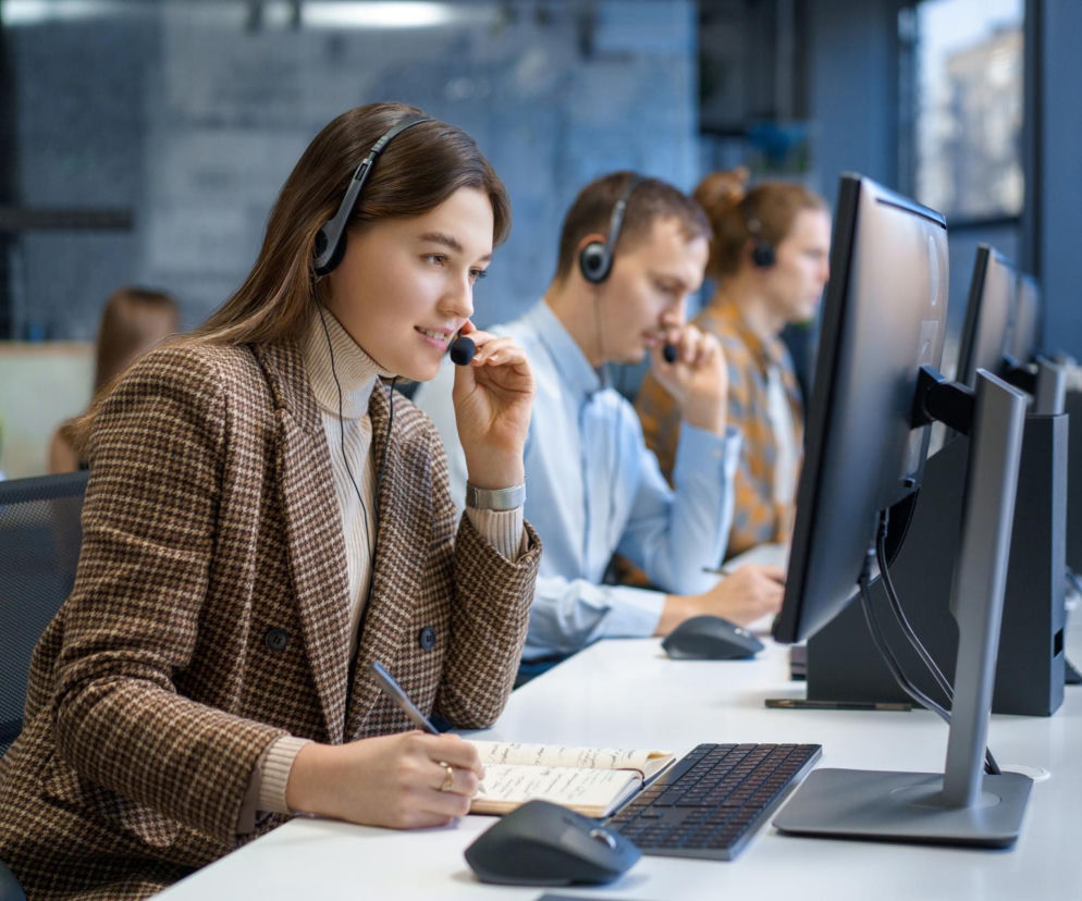 Pracownicy call center w słuchawkach rozmawiają przez telefon. O zakazie telemarketingu we Francji przeczytasz w Eskice.