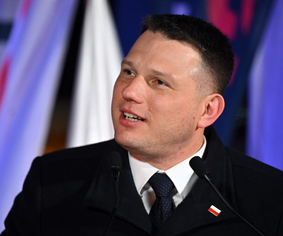 Sławomir Mentzen, polityk i przedsiębiorca, podczas wystąpienia publicznego, z uśmiechem na twarzy i mikrofonem przy ustach. Jego kancelaria szuka pracowników, a o szczegółach tej rekrutacji przeczytasz na Super Biznes.