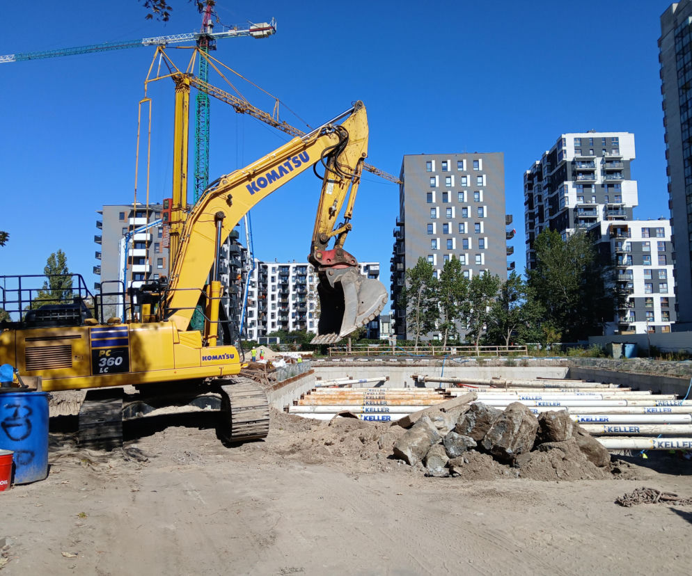Żółta koparka na placu budowy Osiedla Omulewska w Warszawie. O recyklingu materiałów z hotelu Felix przeczytasz w Architektura.