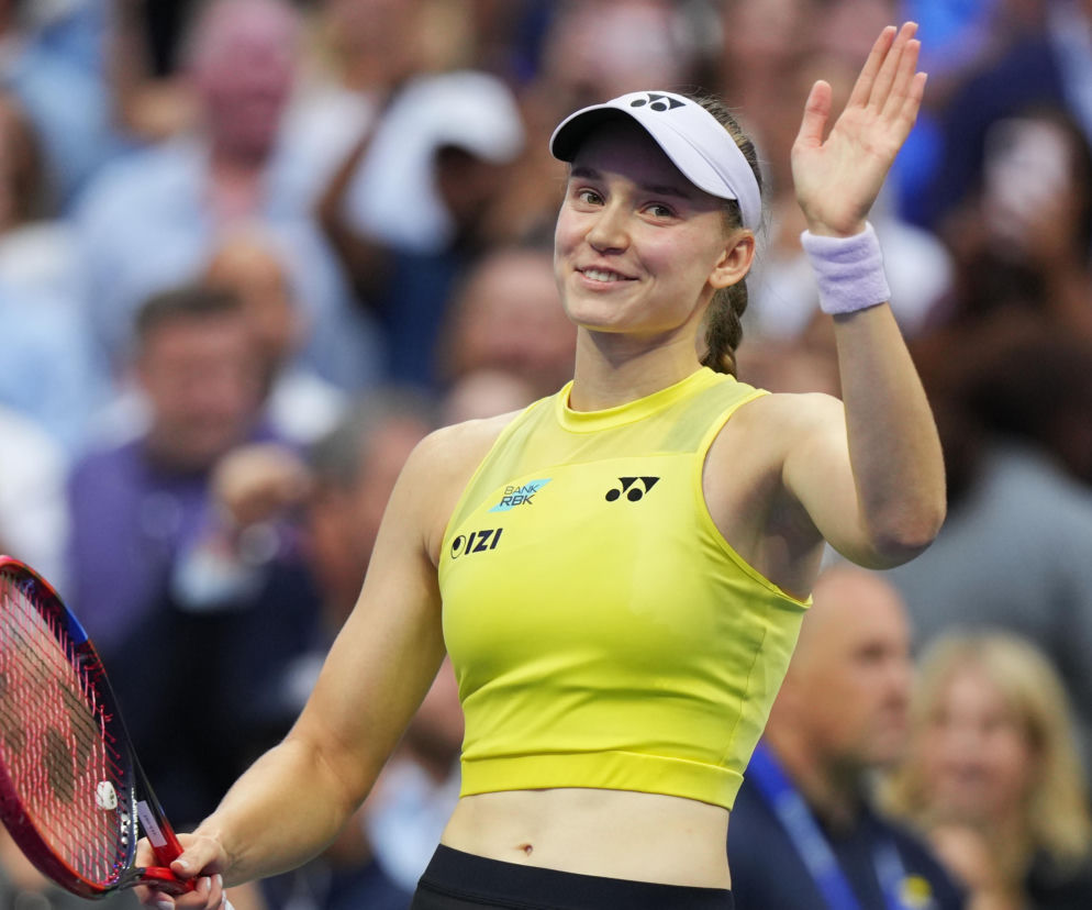 Uśmiechnięta Jelena Rybakina w żółtym stroju macha do kibiców. O jej sukcesie na US Open przeczytasz na SE.