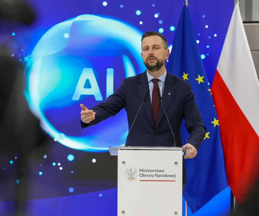 Władysław Kosiniak-Kamysz, szef MON, przemawia z mównicy Ministerstwa Obrony Narodowej. Za nim flagi Polski, UE i NATO oraz ekran z napisem AI. Wicepremier zapowiada 190 mld zł na polską armię z programu SAFE. Więcej o tym przeczytasz na Super Biznes.