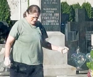 Krystyna Pawłowicz sprząta na grobie rodzinnym