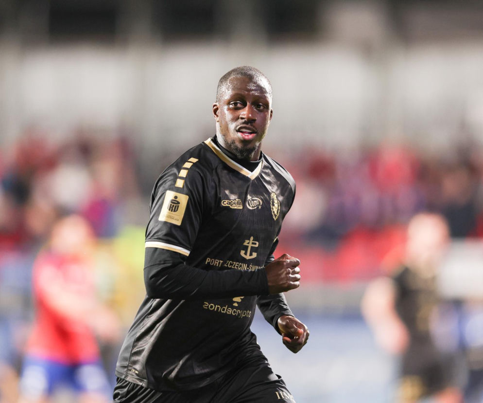 Piłkarz Benjamin Mendy w czarnym stroju Pogoni Szczecin biegnie po murawie stadionu. O jego formie przeczytasz w serwisie Eska.