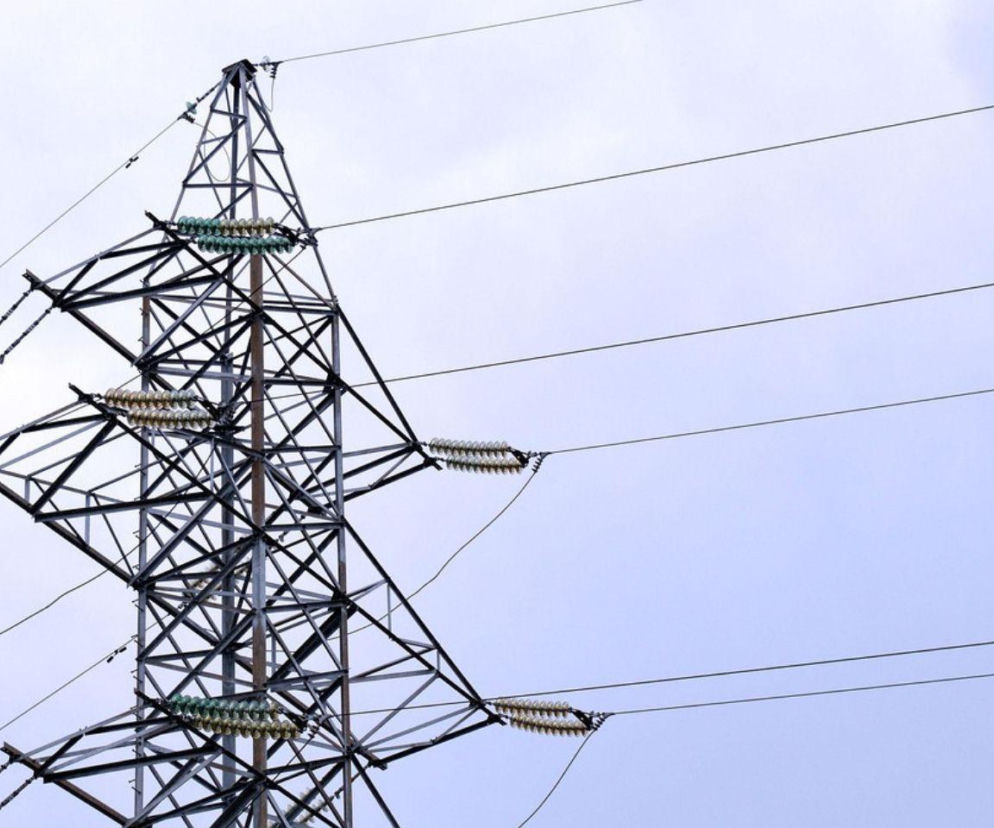 Słup wysokiego napięcia z liniami energetycznymi na tle nieba. O podatkach dla firm energetycznych czytaj na SE Superbiz.