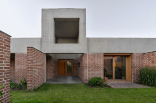 Ściany oplatają fasadę domu z cegły, a nawet przenikają do wnętrza, przekształcając się w ściany nośne. Dom w Mławie