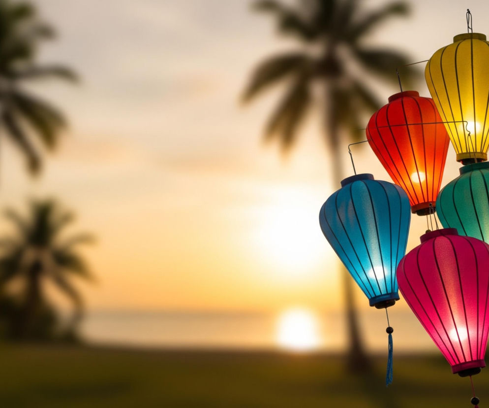 W prawym centrum obrazu znajduje się grupa sześciu kolorowych lampionów. Cztery lampiony mają wydłużony, spiczasty kształt u góry, a dwa dolne lampiony są bardziej zaokrąglone. Lampiony są w kolorach: żółtym, dwóch odcieniach czerwieni, turkusowym, niebieskim i fioletowym, wszystkie emitują ciepłe, jasne światło, podkreślające ich pionowe żebra. Tło, rozmyte i nieostre, przedstawia krajobraz tropikalny o zachodzie słońca, z palmami o ciemnych sylwetkach po lewej stronie i jaśniejącym słońcem odbijającym się w spokojnej wodzie, która rozciąga się w oddali.