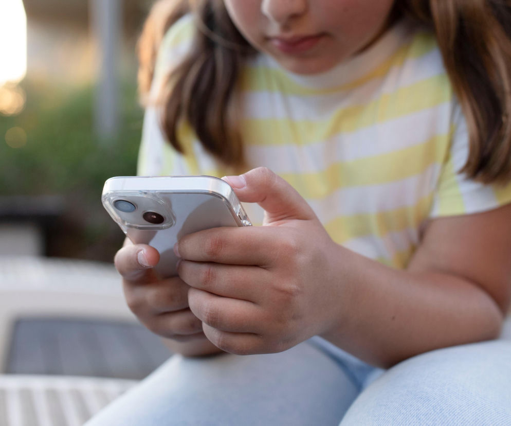 Dłonie dziecka trzymającego smartfon. O wpływie internetu na młodych ludzi przeczytasz na Mediateka.