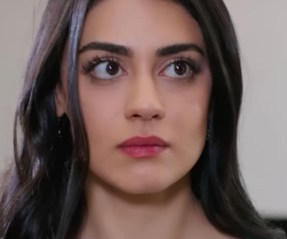 Kobieta o ciemnych, długich włosach i wyrazistym makijażu, z przerażeniem wpatrująca się w bok, na jej ustach widoczny różowy błyszczyk, a oczy szeroko otwarte, co oddaje emocje związane z kryzysem Hancer i Cihana w serialu Panna młoda, o którym przeczytasz na Super Seriale.