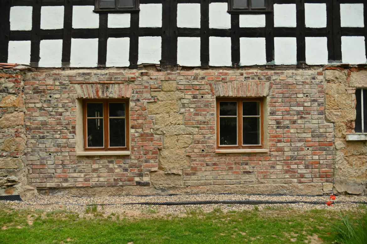 Dom w Twardocicach - remont przywraca zabytkowi dawny wygląd. Widać gruntownie wyremontowaną fasadę i zniszczoną ścianę wschodnią, na której renowację zabytek otrzymał dotację z MKiDN
