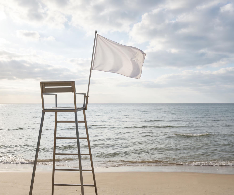 Wieża ratownicza z białą flagą na pustej plaży w Łazach. O warunkach nad Bałtykiem przeczytasz na SE Szczecin.