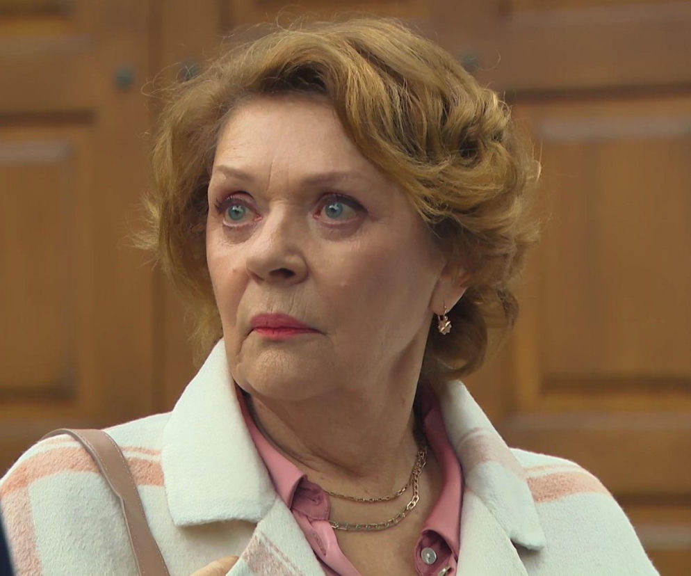 Elżbieta Jarosik jako Józefina z serialu Barwy szczęścia w zbliżeniu, nosząca różową koszulę, jasny płaszcz w paski i złoty naszyjnik, z intensywnym wyrazem twarzy. Artykuły o jej losach znajdziesz na stronie Super Seriale.