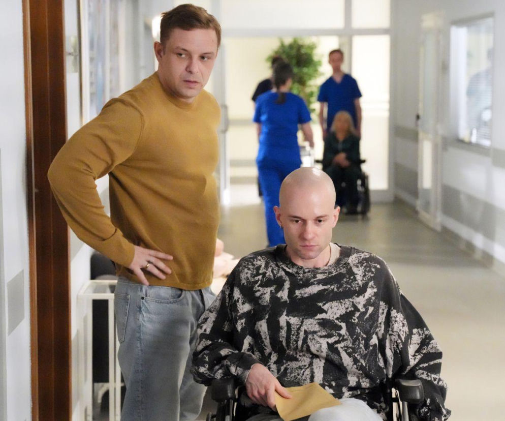 Hubert w miodowym swetrze stoi obok Adama na wózku inwalidzkim w szpitalu. O ich kłótni przeczytasz na Eska.