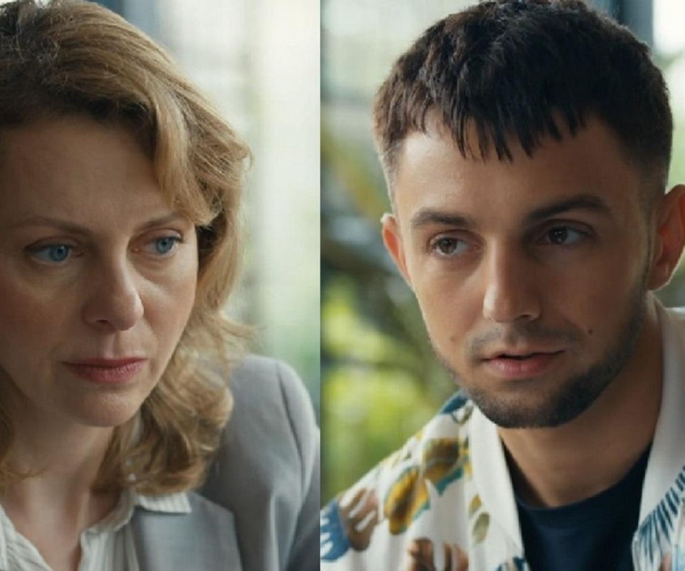 Dorota Kujawiak (Karina Seweryn) z zaniepokojeniem patrzy w dół, jej twarz wyraża smutek, na drugim planie Mirek Wójcik (Oliwier Kozłowski) z serialu Barwy szczęścia w koszuli z liśćmi, patrzący w bok. Więcej o ich relacji na Super Seriale.
