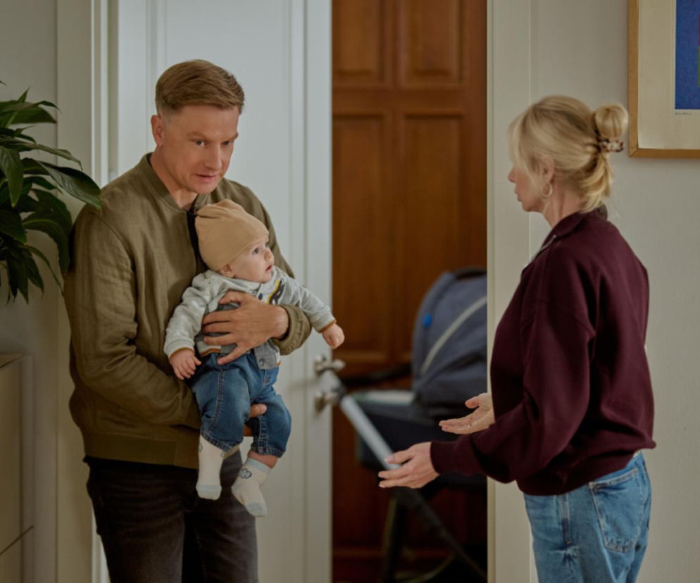 Igor Nowak z synem Jasiem na rękach w trakcie rozmowy z Ewą Ostrowską w 4130 odcinku Na Wspólnej. Ewa próbuje przekonać Igora, by chronił Jasia przed Anką, ale on nie chce słuchać. Więcej o losach bohaterów Super Seriale.