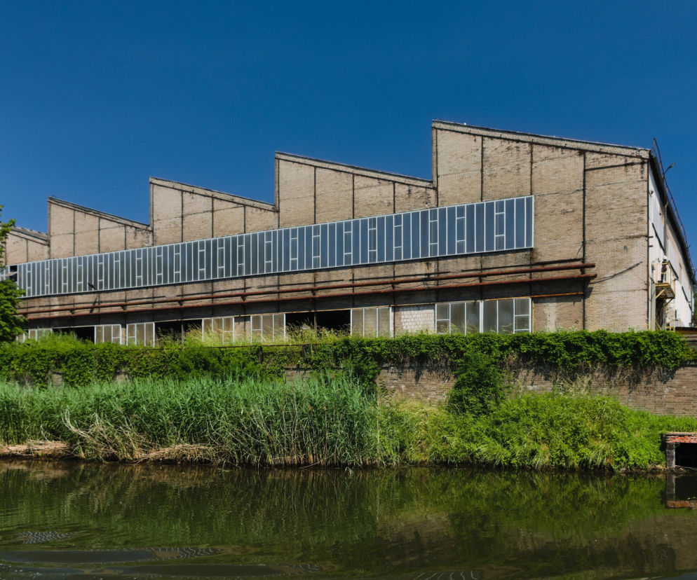 Ceglany budynek huty nad rzeką. O planach modernizacji polskich hut przez Węglokoks przeczytasz na Muratorplus.