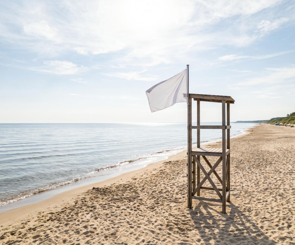 Pusta wieża ratownicza z białą flagą na słonecznej plaży w Rewalu. O bezpieczeństwie w wodzie przeczytasz na SE Szczecin.