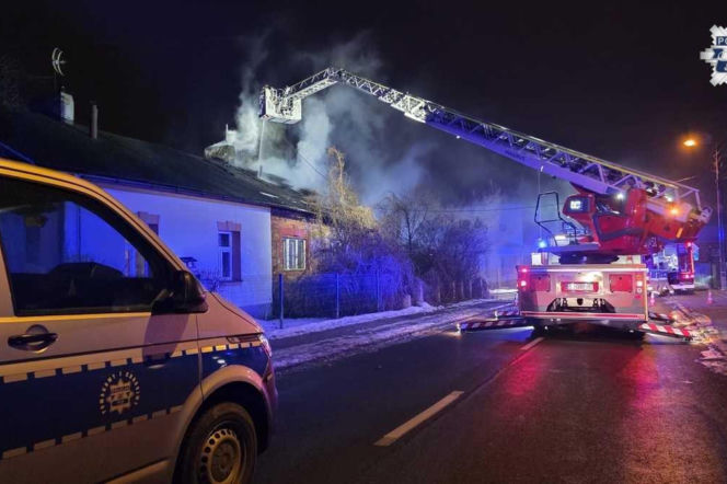 Strażacy gaszący pożar domu w Jaworznie z wysięgnika. Obok radiowóz policji. O akcji ratunkowej czytaj w Eska Śląskie.