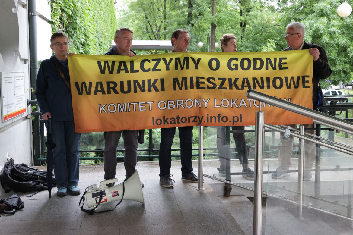 "Walczymy o godne warunki mieszkaniowe" mówi flaga, którą przynieśli mieszkańcy