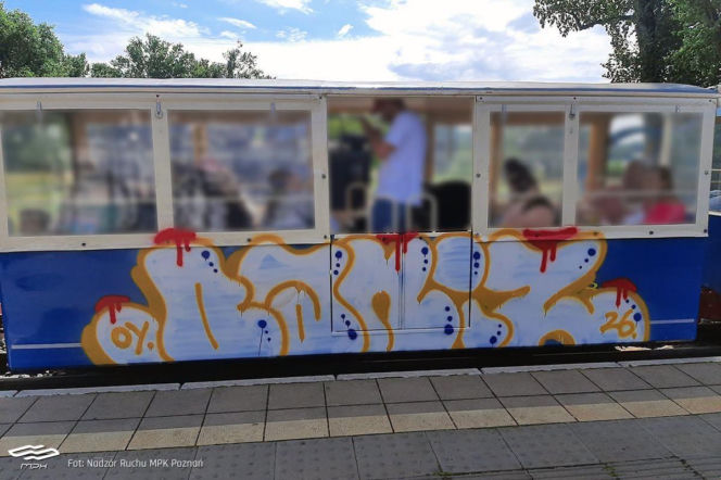 Niebieski wagonik kolejki Maltanka z dużym, kolorowym graffiti na boku. O wandalizmie w Poznaniu przeczytasz na SE.