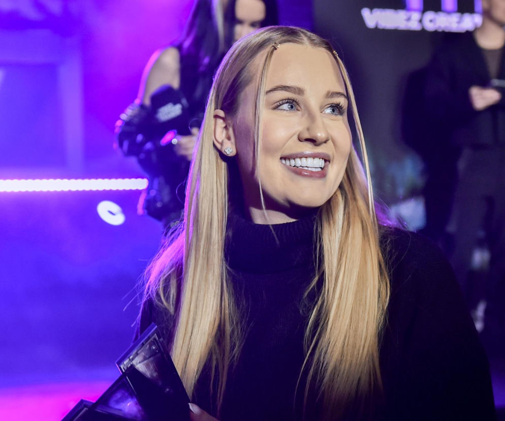 Uśmiechnięta influencerka Andziaks w czarnym golfie. O jej zarobkach z YouTube przeczytasz na SE.