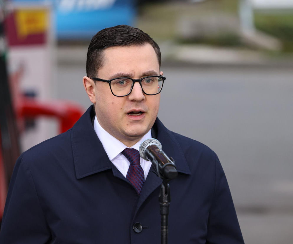 Minister Miłosz Motyka w okularach przemawia do mikrofonu. O programie CPN i cenach paliw przeczytasz na Eska.