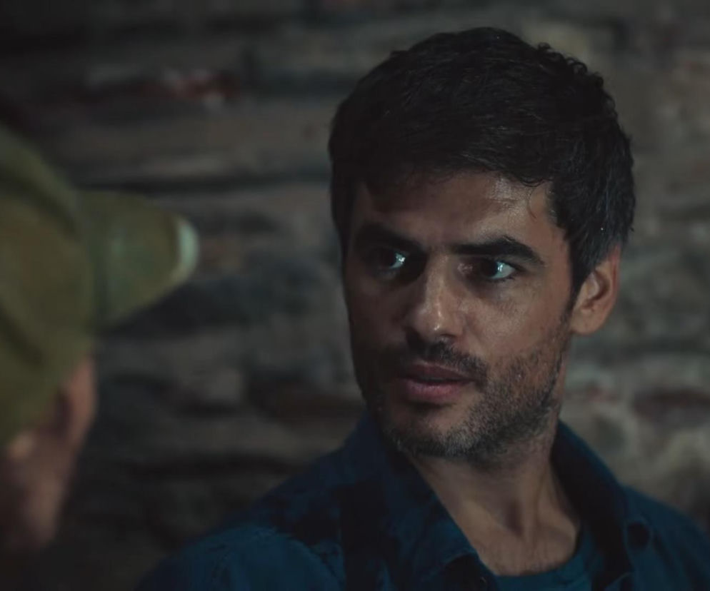 Mężczyzna, Poyraz, z zaniepokojeniem spogląda na Nanę, którą widać z boku kadru, co odzwierciedla napięcie w 873. odcinku serialu Dziedzictwo. Obaj bohaterowie są w kryjówce, a w tle widać ciemną ścianę z cegieł. Więcej informacji o serialu na stronie Super Seriale.