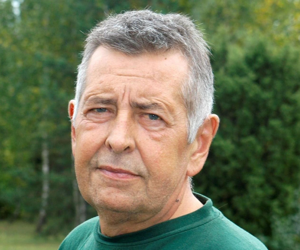 Portret dojrzałego Tadeusza Nalepy z krótkimi, siwymi włosami na tle zieleni. O legendzie bluesa przeczytasz na EskaRock.
