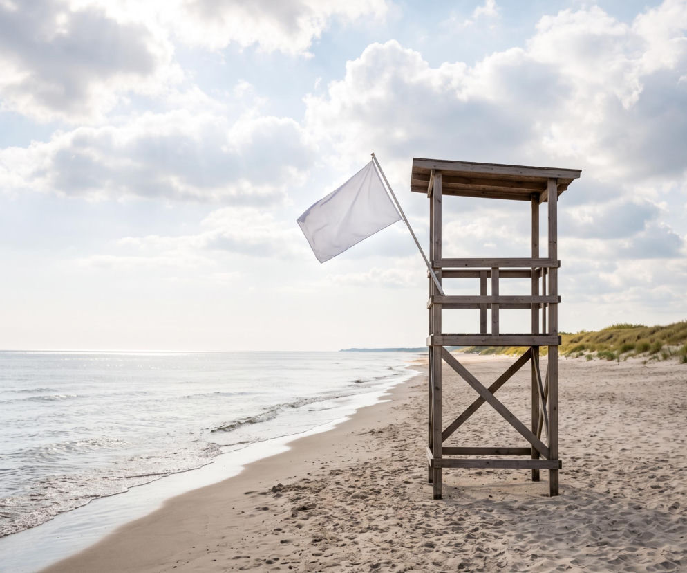 Biała flaga na wieży ratowniczej na pustej plaży w Grzybowie. O warunkach nad wodą przeczytasz na SE Szczecin.