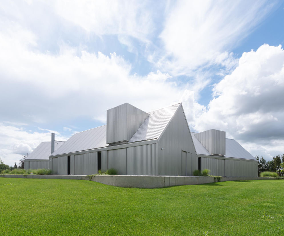 Dom Ultra o elewacji z blachy falistej na tle zielonej trawy i nieba. O nowoczesnej bryle przeczytasz na Architektura.