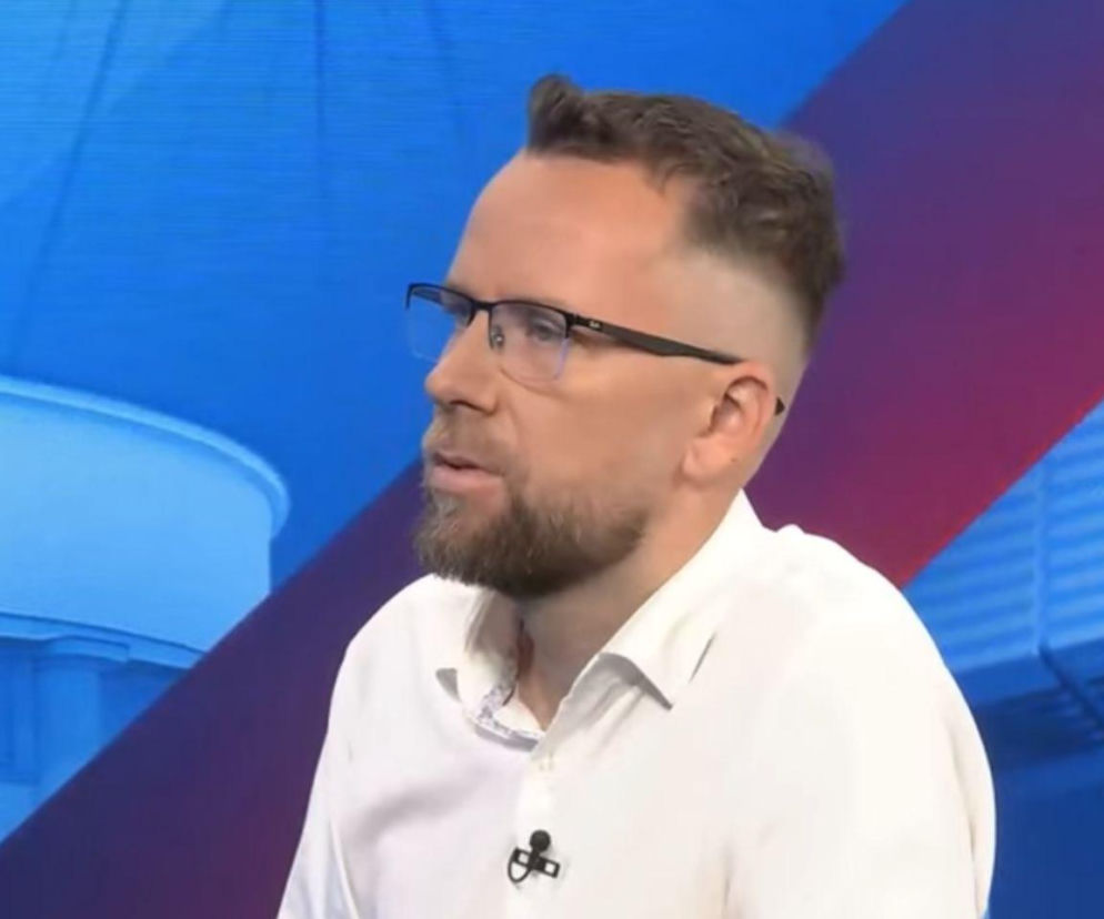 Maciej Wilk w białej koszuli i okularach podczas wywiadu. O referendum w Warszawie przeczytasz na SE.