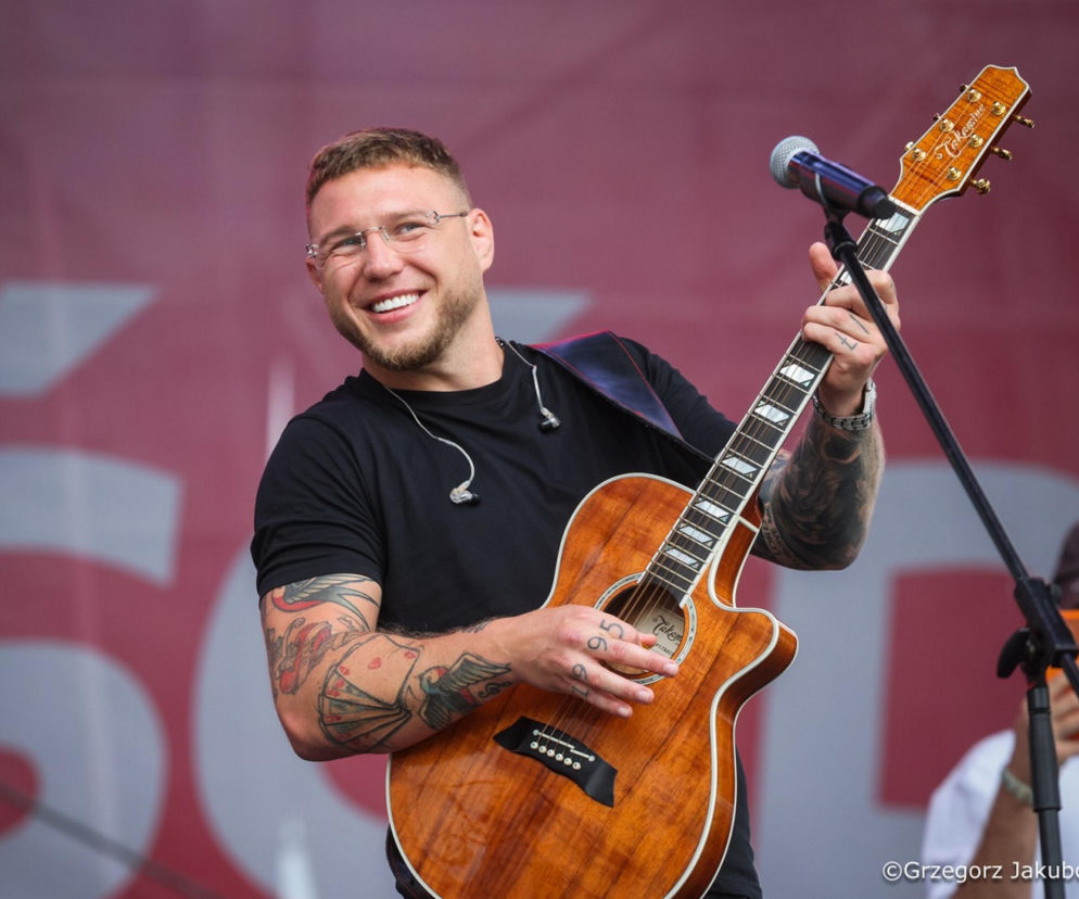Uśmiechnięty raper Kubańczyk z gitarą na scenie w Juracie. O występie dla prezydenta Nawrockiego przeczytasz w SE.
