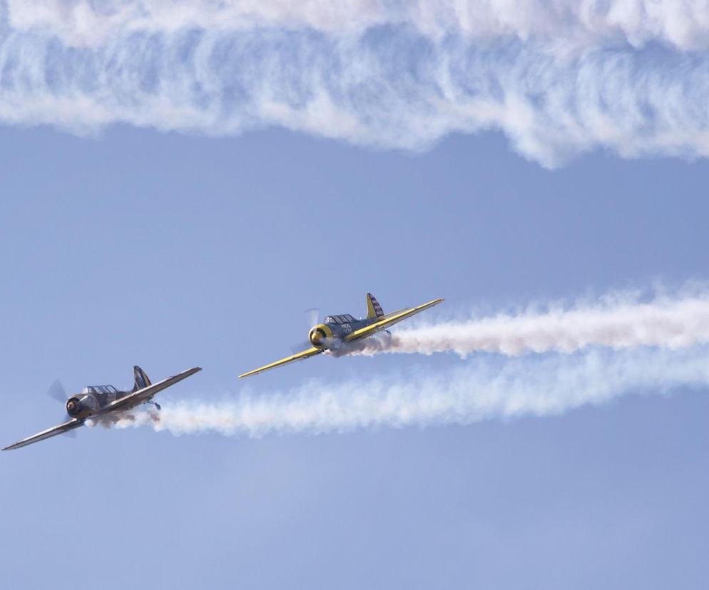 Dwa samoloty wykonują akrobacje na niebie, zostawiając smugi dymu. O odwołaniu Air Show przeczytasz na SE Portal Obronny.