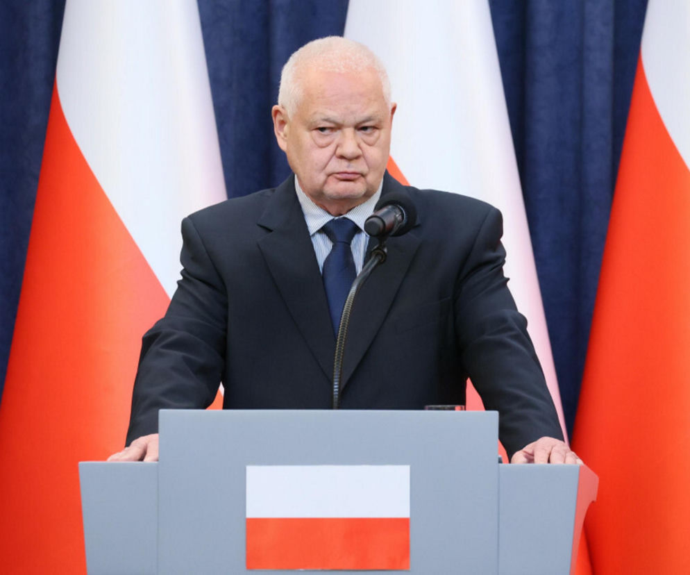 Prezes NBP Adam Glapiński podczas konferencji prasowej przedstawiający prognozy inflacji i wzrostu PKB do 2028 roku. Za nim widoczne są flagi Polski. O najnowszych danych z raportu NBP przeczytasz na Super Biznes.