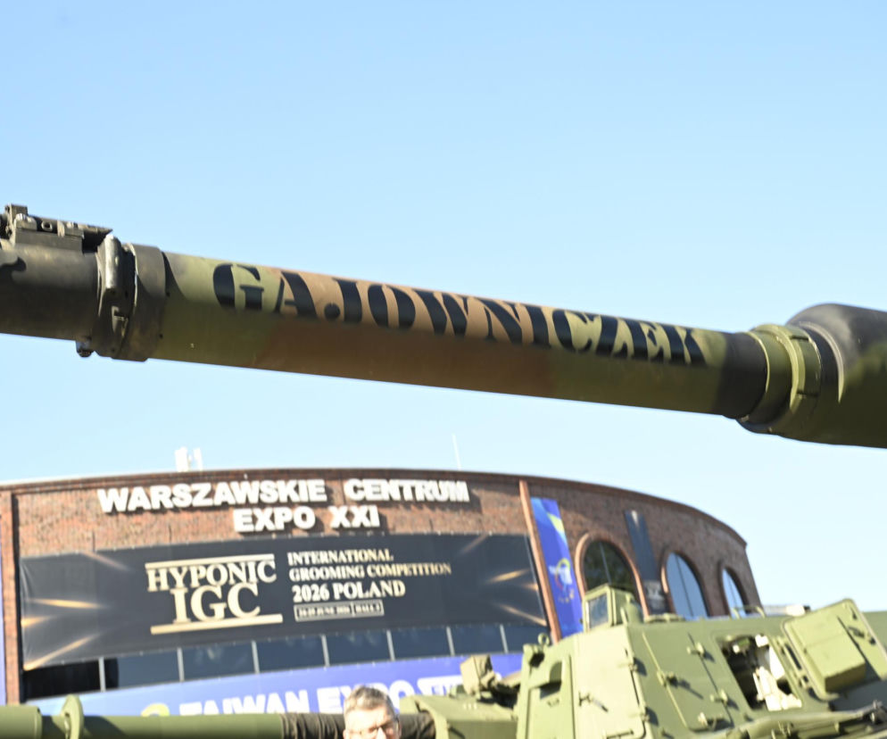 Lufa czołgu Abrams z kamuflażem, na której widnieje czarny napis Gajowniczek, symbolizujący bohatera artykułu, wystawiona na tle budynku Warszawskie Centrum EXPO XXI podczas targów obronnych. Więcej o nazwach czołgów na naszym portalu.