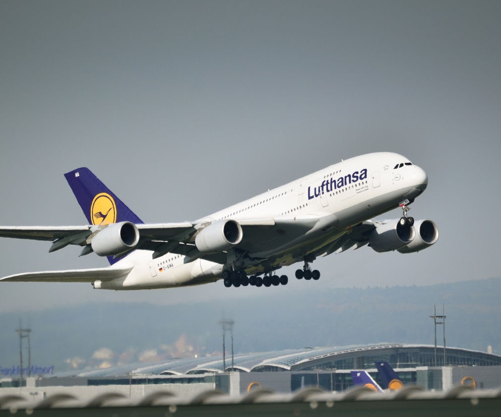 Samolot Airbus A380 Lufthansy startujący z lotniska. Maszyna wznosi się w powietrze, widoczne podwozie i charakterystyczne logo linii lotniczych na ogonie. Na portalu Super Biznes przeczytasz o zmianach w przepisach dotyczących powerbanków na pokładach Lufthansy.