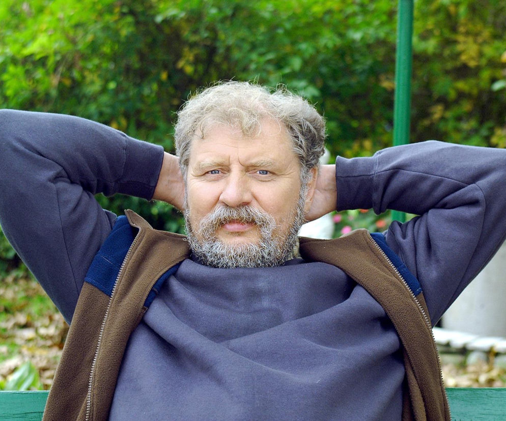 Aktor Andrzej Grabowski z rękami za głową siedzi na ławce. O metamorfozach gwiazd filmu przeczytasz na SE.
