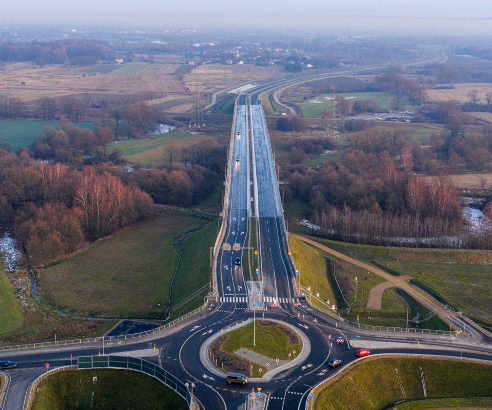 Obwodnica Oświęcimia z nowym mostem na Sole, widziana z lotu ptaka. Na zdjęciu widać fragment nowoczesnej infrastruktury drogowej, rondo, estakadę i otaczające tereny zielone, przygotowane do oddania do użytku. Więcej o inżynierskich majstersztykach na portalu Architektura Murator Plus.